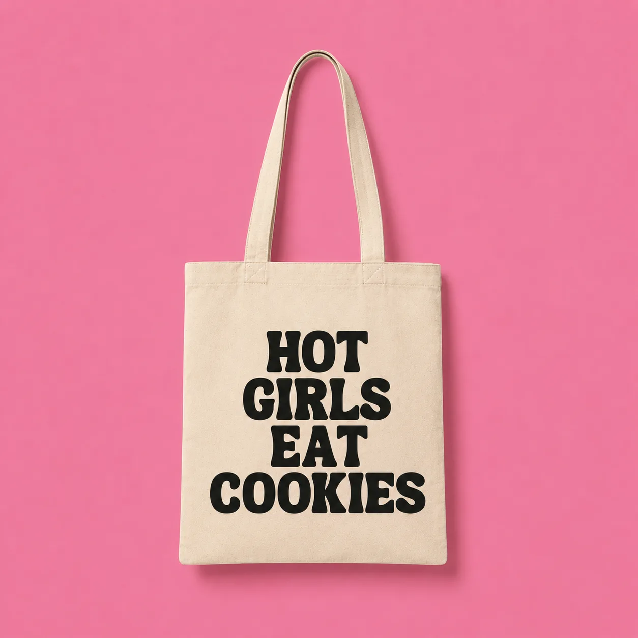 Cream canvas tote reading Hot Girls Eat Cookies on a pink background